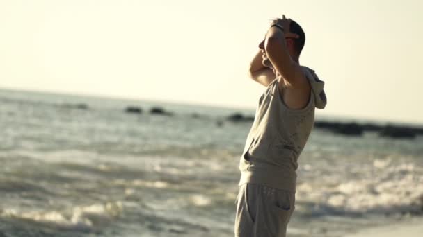 Férfi jogger, élvezi a kilátás és a nyújtás karok beach — Stock videók