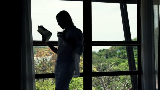 Mujer leyendo periódicos y bebiendo por la ventana — Vídeos de Stock