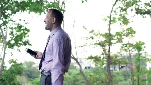 Бізнесмен слухає музику і танцює на терасі — стокове відео