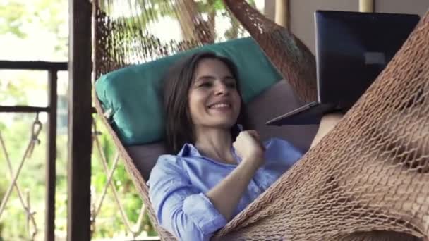 Vrouw chatten op laptop op hangmat op terras — Stockvideo