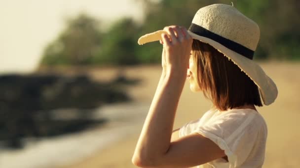 Vrouw met hoed van de zomer genieten van zonsondergang op het strand — Stockvideo