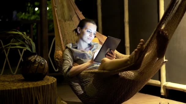 Woman with tablet computer lying on hammock — Stock Video