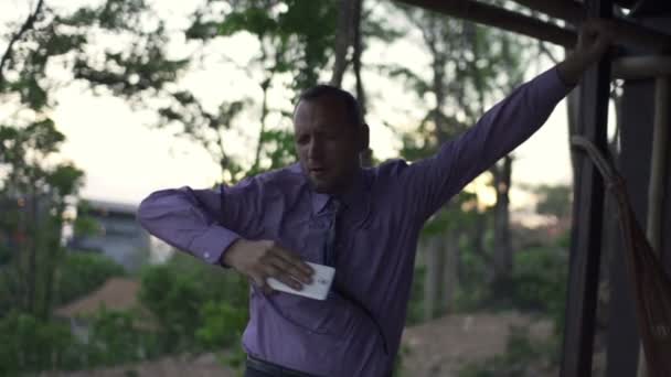 Бізнесмен слухає музику, танцює на терасі — стокове відео