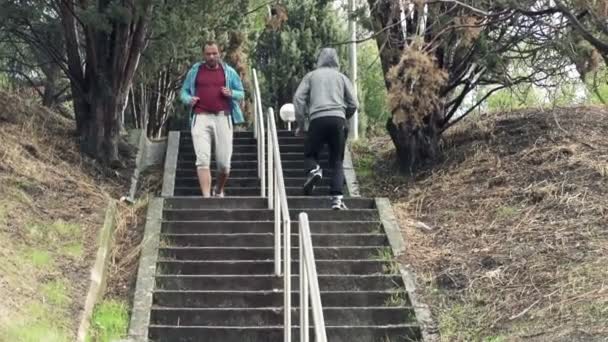 Twee mannen die de trap in park joggen — Stockvideo