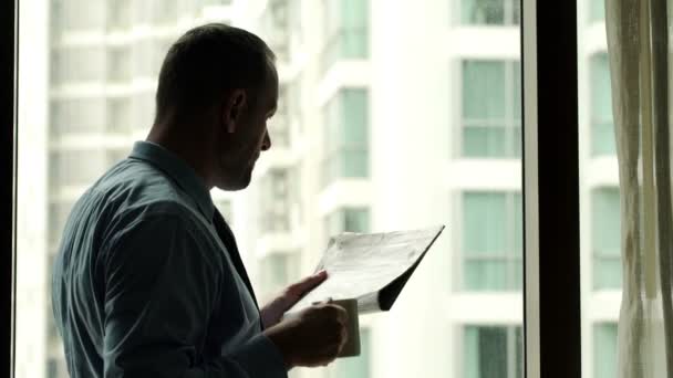 Businessman reading newspaper and drinking coffee — Stock Video