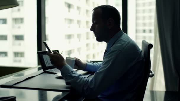 Hombre de negocios con teléfono inteligente beber café por mesa — Vídeos de Stock