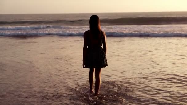 Günbatımı sırasında denize yürüyen kadın — Stok video