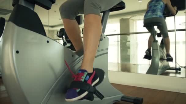 Mujer montar bicicleta estacionaria en el gimnasio — Vídeo de stock