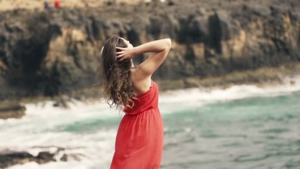 Женщина играет со своими волосами, стоящими у моря — стоковое видео