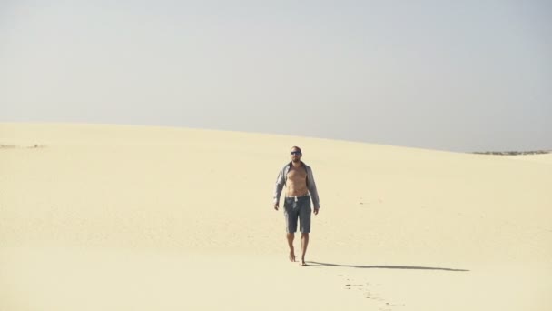 Потерянный молодой человек, идущий по пустыне — стоковое видео