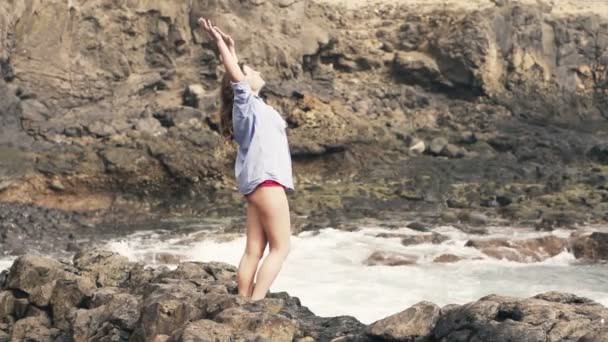 Γυναίκα απολαμβάνοντας τον εαυτό της στέκεται σε βράχια κοντά στη θάλασσα — Αρχείο Βίντεο