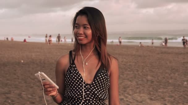 Mujer asiática escuchando música en playa — Vídeo de stock
