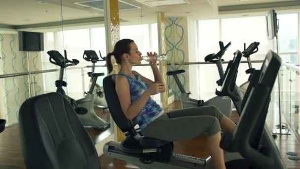 Vrouw drinkwater op upright bike — Stockvideo