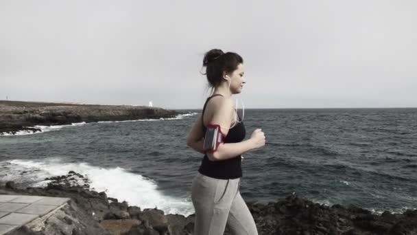 Mujer corriendo a través del paseo marítimo por el mar — Vídeos de Stock