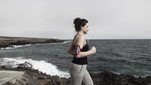 Mujer corriendo a través del paseo marítimo por el mar — Vídeo de stock