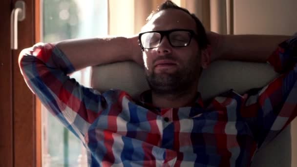 Счастливый мужчина отдыхает на стуле дома — стоковое видео