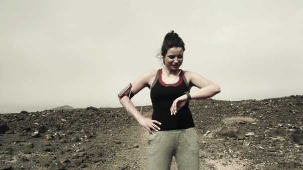 Happy female jogger standing on desert — Stock Video