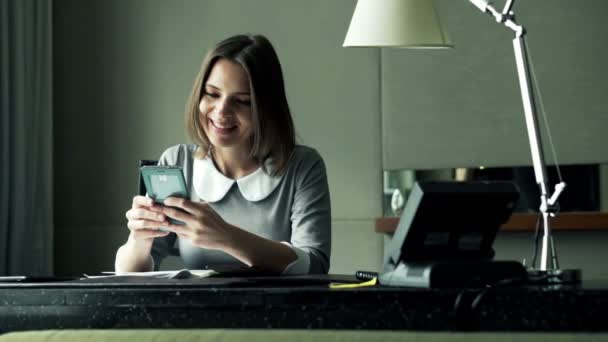 Businesswoman with smartphone sitting by desk at the office — Stock Video