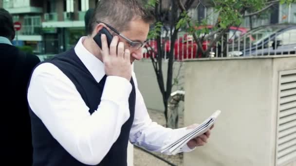 Angry businessman with cellphone and newspaper in the city — Stock Video