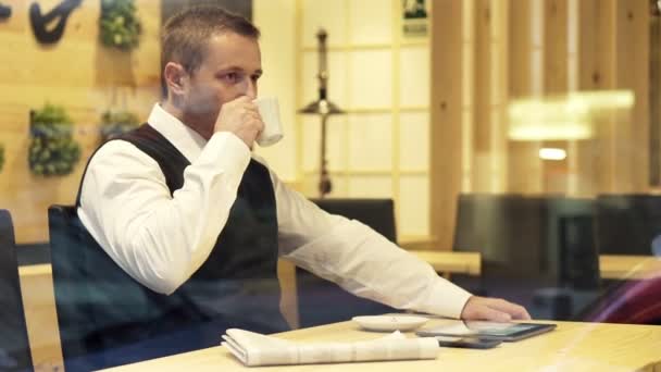 Бизнесмен пьет кофе сидя в кафе — стоковое видео