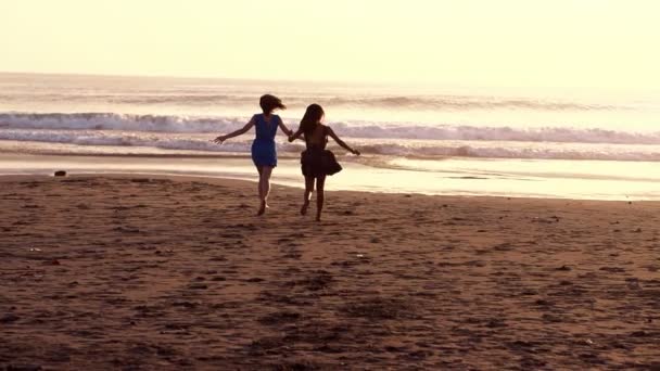 Две девушки бегут по пляжу — стоковое видео