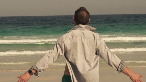 Hombre con los brazos abiertos en la playa — Vídeos de Stock