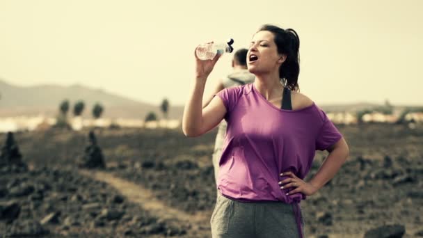 Drinkwater van vrouw en man joggen op woestijn — Stockvideo