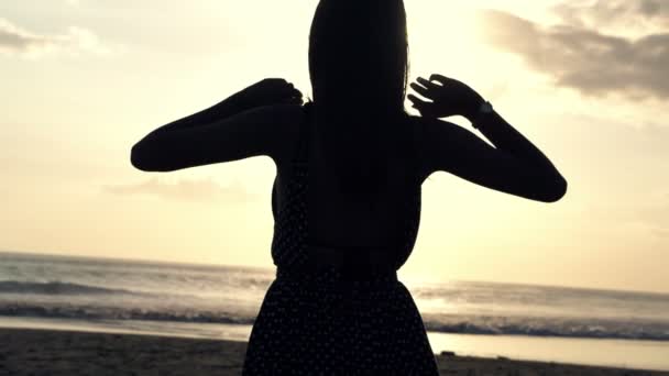 Mujer disfrutando de la puesta de sol mientras está de pie en la playa — Vídeo de stock