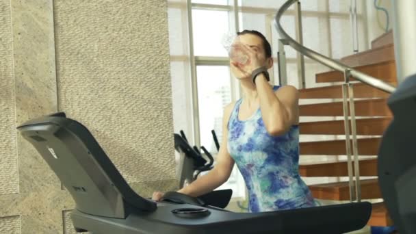 Woman drinking water on treadmill in gym — Stock Video