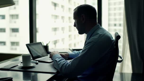 Бізнесмен працює на ноутбуці, сидячи за столом — стокове відео