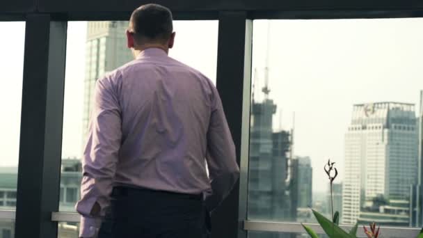 Успешный бизнесмен на крыше смотрит на городской пейзаж — стоковое видео