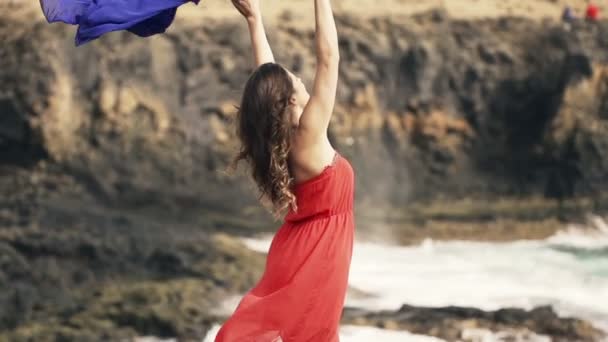 Женщина с парео стоит на скалах у моря — стоковое видео
