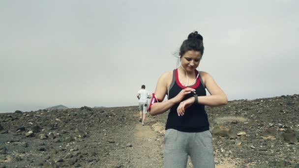 Mujer con smartwatch y hombre corriendo en el desierto — Vídeo de stock