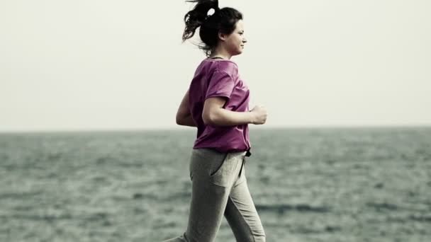 Mujer corriendo a través del paseo marítimo por el mar — Vídeo de stock