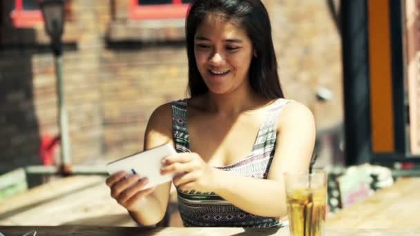 Женщина играет в игру на смартфоне в кафе — стоковое видео
