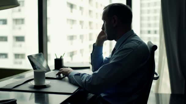 Empresário trabalhando com laptop e celular no escritório — Vídeo de Stock