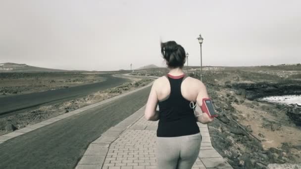 Женщина бегает по набережной морем — стоковое видео