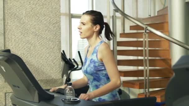 Femme en cours d'exécution sur machine tapis roulant dans la salle de gym — Video