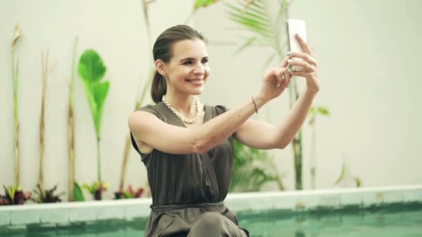 Mulher tirando foto selfie com celular por piscina — Vídeo de Stock