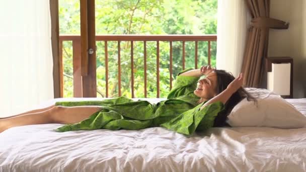 Mutlu kadın yatakta yatarken bornoz — Stok video
