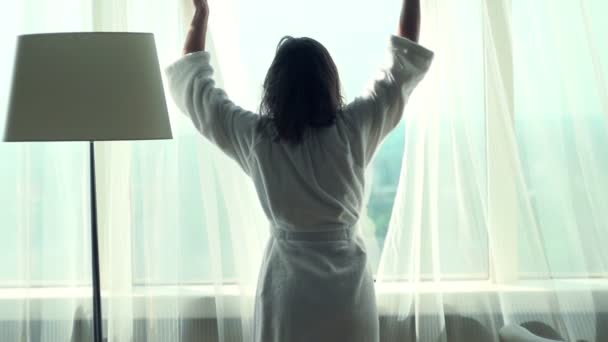 Женщина открывает занавески любоваться видом из окна — стоковое видео