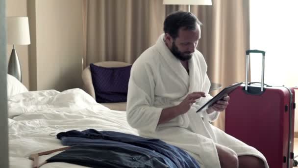 Empresário usando tablet computador sentado na cama — Vídeo de Stock