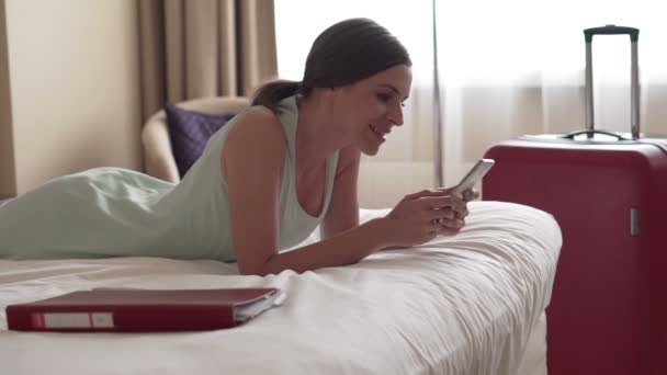 Businesswoman using smartphone lying on bed — Stock Video