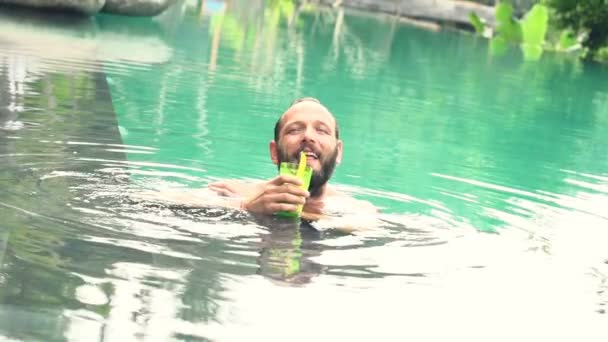 Hombre levantando brindis a cámara en piscina — Vídeos de Stock
