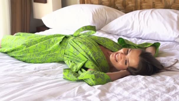 Женщина в халате лежит на кровати — стоковое видео