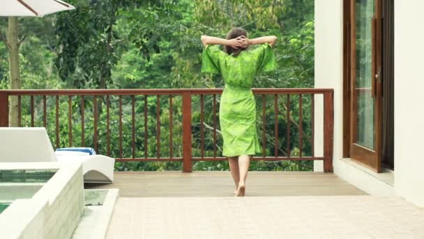 Frau im Bademantel auf der Terrasse streckt die Arme aus — Stockvideo