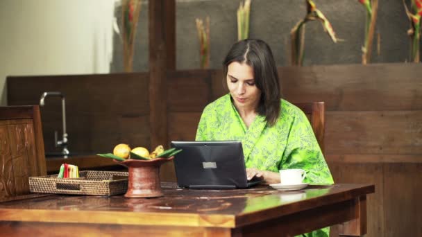 Mujer usando un portátil moderno por mesa en la cocina — Vídeos de Stock