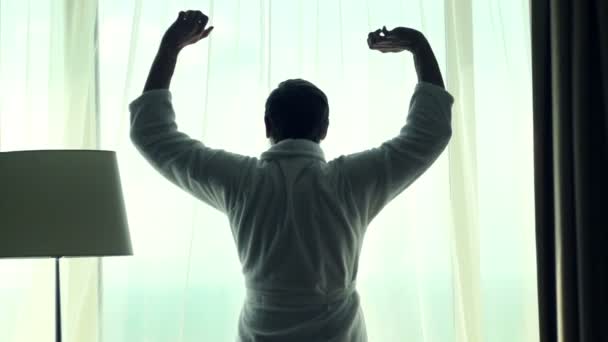 Homem esticando os braços de pé pela janela — Vídeo de Stock