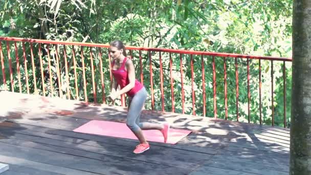 Женщина осуществляет прыжок боком на террасе — стоковое видео