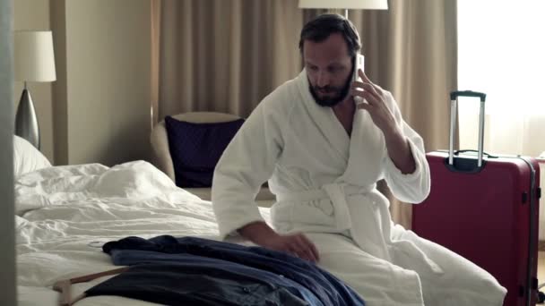 Businessman talking on cellphone sitting on bed — Stock Video